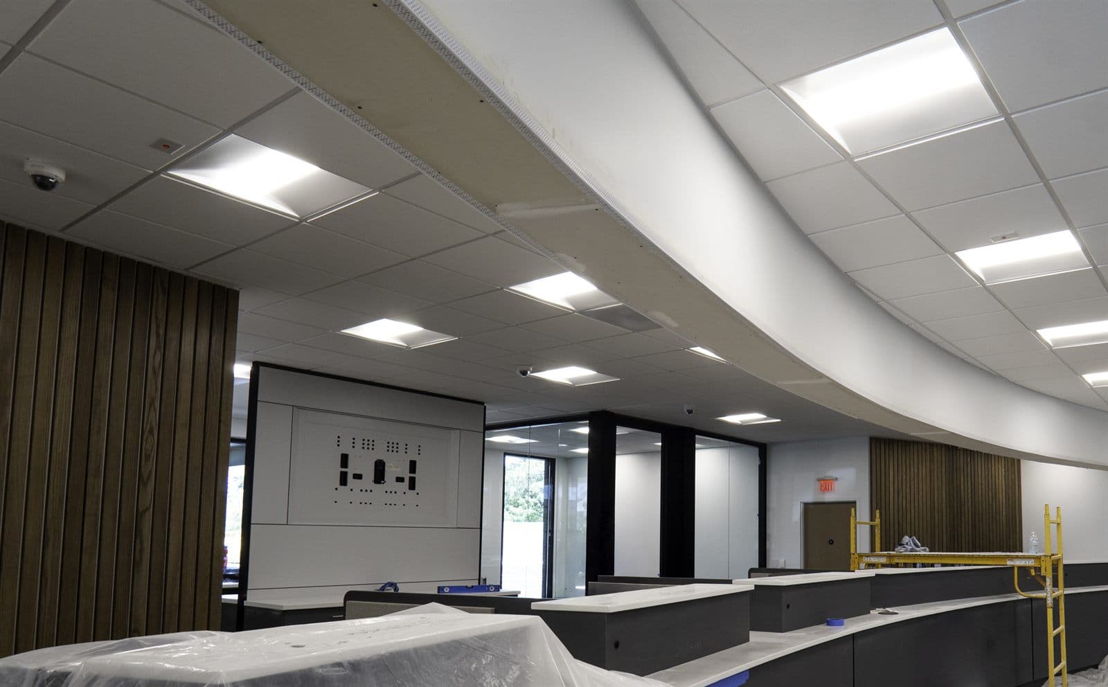 Curved suspended acoustical grid ceiling with integrated lighting over a finished commercial space