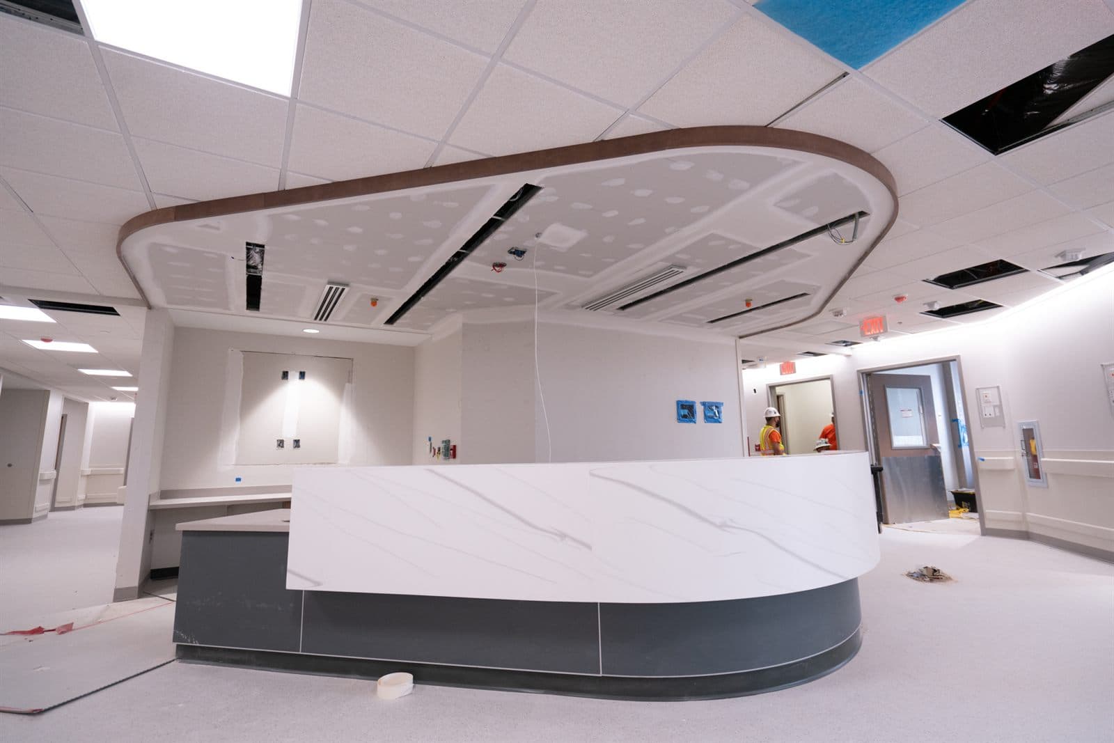 Finished reception area with a floating curved acoustical cloud above the front desk