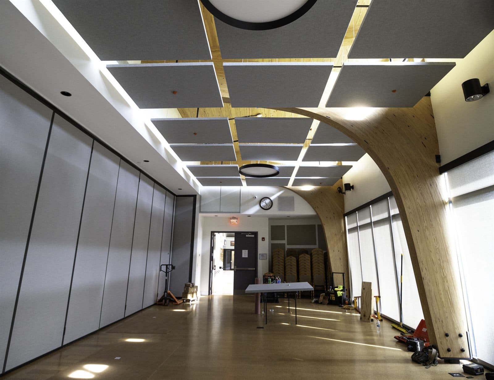 Corridor with a curved wood-slat feature ceiling and recessed circular lighting